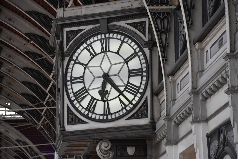 Inside a large, historic railway station with a high, arched metal and glass ceiling illuminated by artificial lighting, showing a spacious waiting area with polished tiled floors. On the left side, t